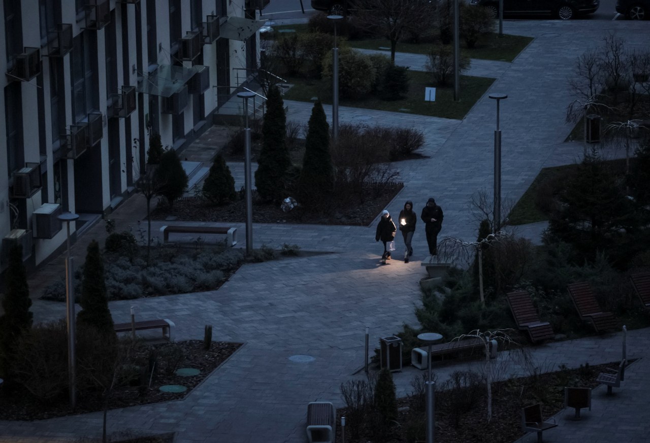 People use a flashlight to walk through a darkened area in Kyiv during a blackout.