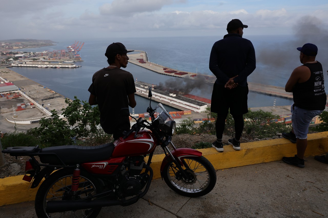 People on Saturday watched smoke rising from Venezuela’s Port of La Guaira after explosions and low-flying aircraft were heard.