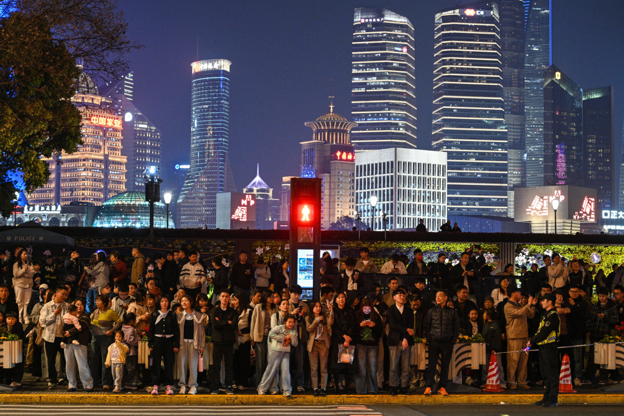 People wait to cross a street in Shanghai.