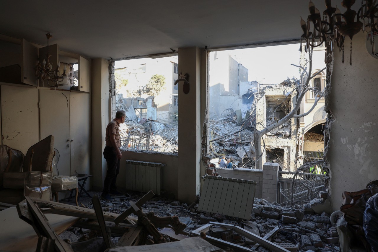 An Iranian resident looks out the window of his damaged home after Israeli-American strikes on April 7.