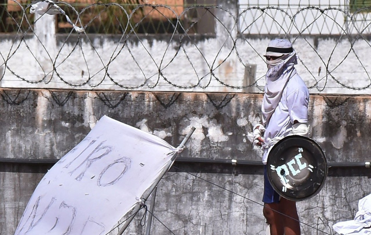 An inmate uses a shield with the initials PCC to protect himself after an uprising broke out at Alcaçuz prison in Natal, Rio Grande do Norte state, Brazil, in 2017.